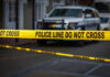 Yellow police tape in front of blurred vehicles