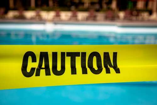 shutterstock_2047514747.jpg Yellow caution tape in front of a swimming pool