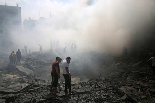 People standing amidst smoke and debris after a disaster