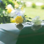 Yellow and white flowers on a green casket