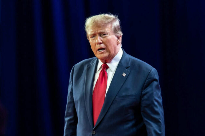 Man in dark suit and red tie speaking