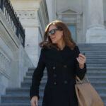 Person in black coat and sunglasses on stairs