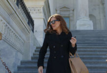 Person in black coat and sunglasses on stairs