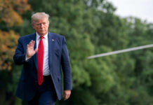 Person in suit walking outdoors waving hand