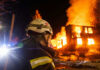Firefighter watches burning building at night scene