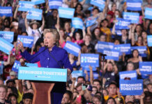Hillary Clinton speaking at a political rally with a cheering crowd