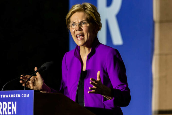 A woman in a purple jacket passionately speaking at a podium during a campaign event
