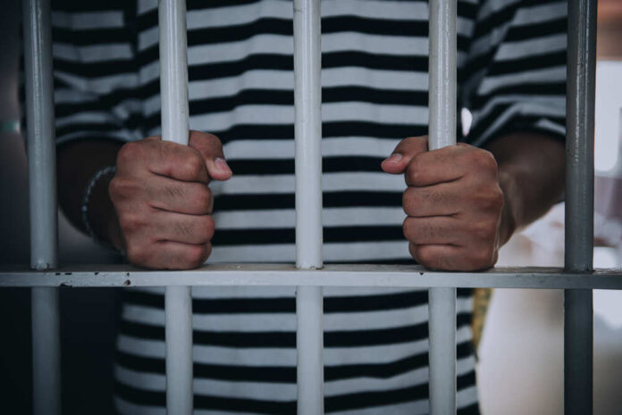 Inmate's hands gripping prison bars