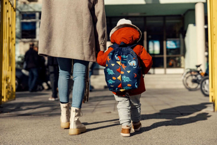 Adult and child walking towards a school building