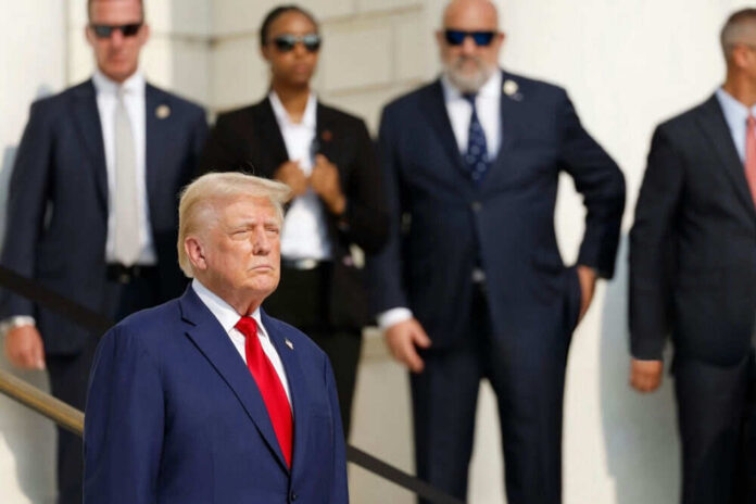 2545412917 Man in blue suit with people in background standing