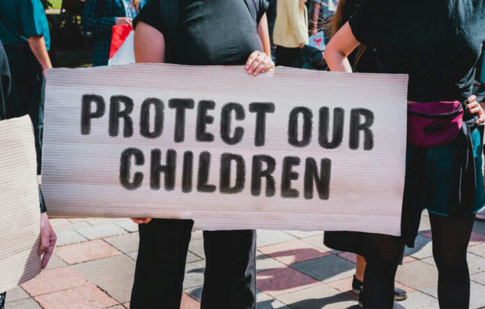 1542859688 Person holding sign reading Protect Our Children