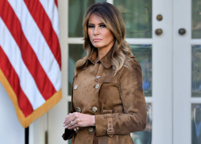 Woman in brown coat standing near American flag