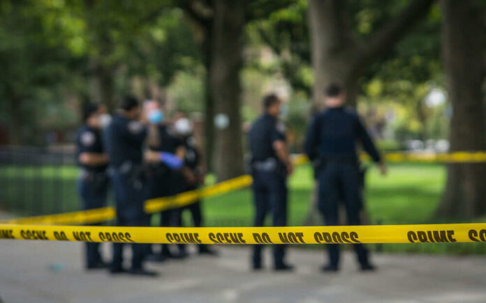 Police officers standing behind crime scene tape outside