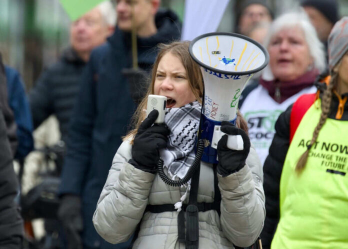 Person holding megaphone at protest with crowd behind