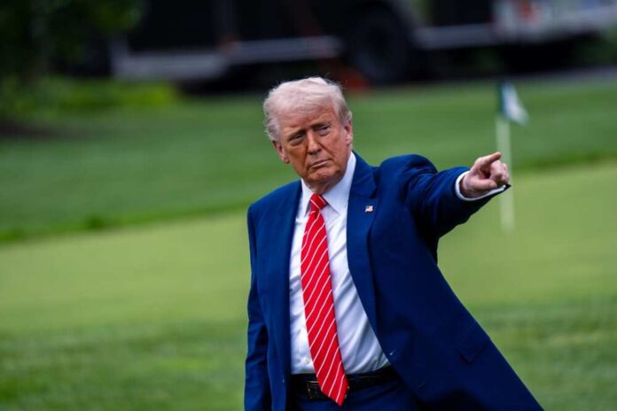 A man in a blue suit and red tie pointing while standing on a golf course