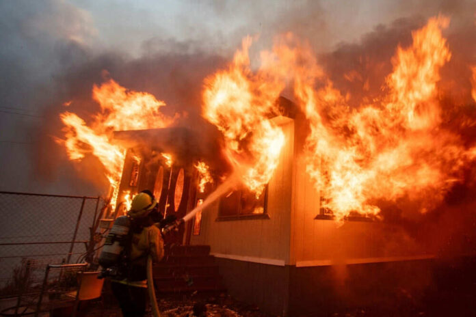 Firefighter extinguishing large house fire blaze