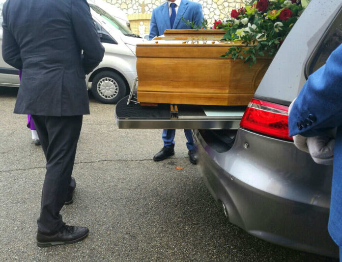 Coffin being placed in a hearse at funeral