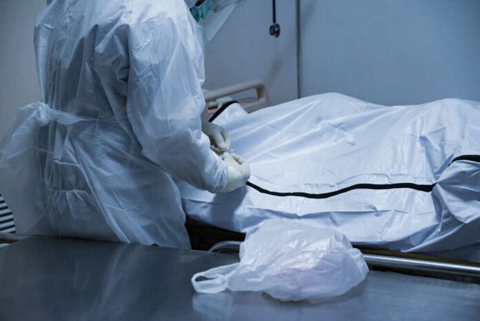 Person in protective gear handling body bag