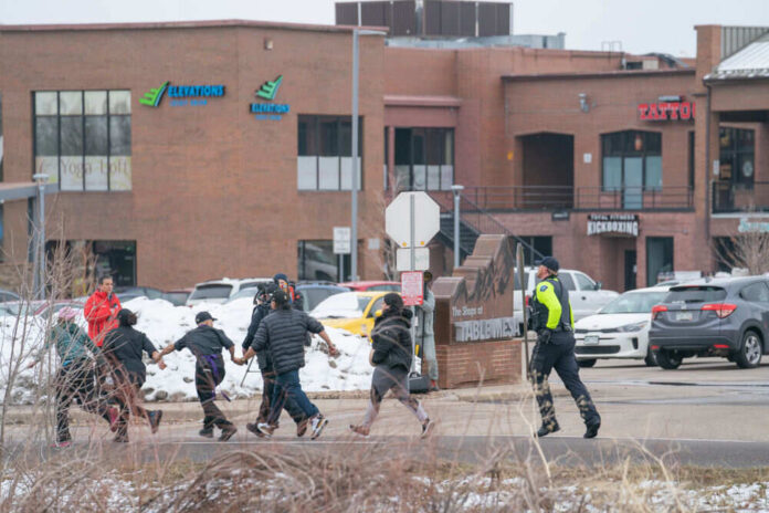 Group walking with police officer near shops and snow
