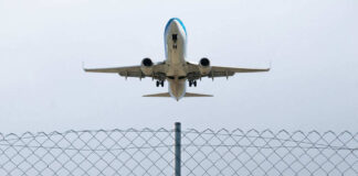 Airplane taking off above a wire fence