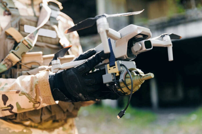 Camouflage soldier holding a drone with accessories attached