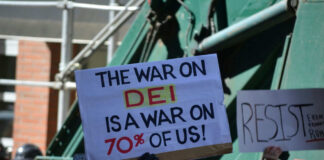 Protesters holding signs including The War on DEI