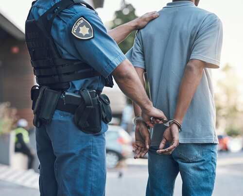 Police officer handcuffing a suspect in a street setting