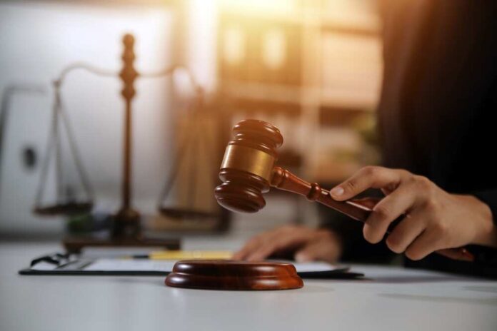 A lawyer striking a gavel on a desk in a courtroom setting