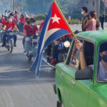 People riding motorcycles and car with Cuban flags