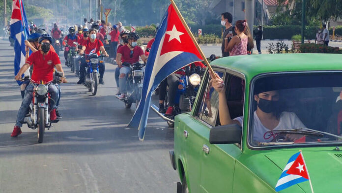 People riding motorcycles and car with Cuban flags