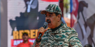 Man in camouflage uniform speaking at event outdoors