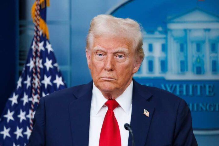 A political figure standing in front of the American flag during a press briefing