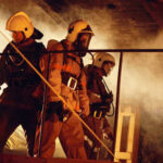 Firefighters in protective gear navigating through smoke