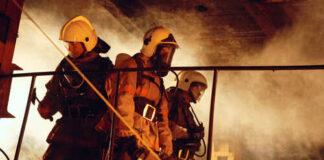 Firefighters in protective gear navigating through smoke