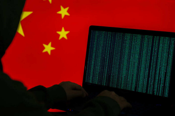 Hacker at laptop with Chinese flag background